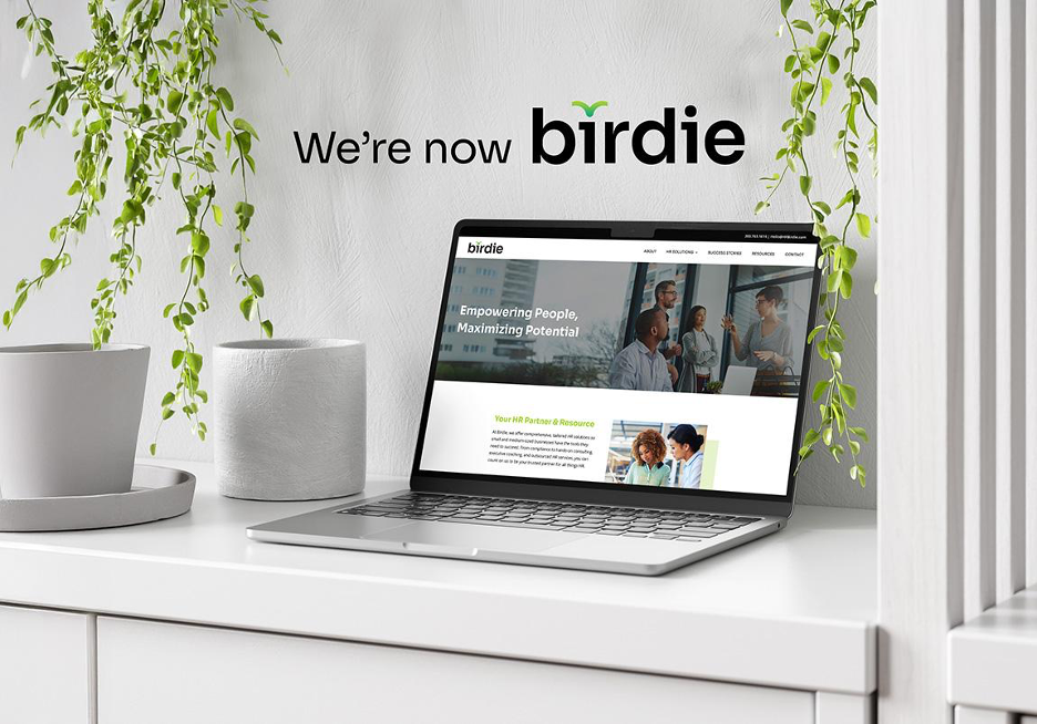 computer on a desk with plants with the word "we're now birdie"