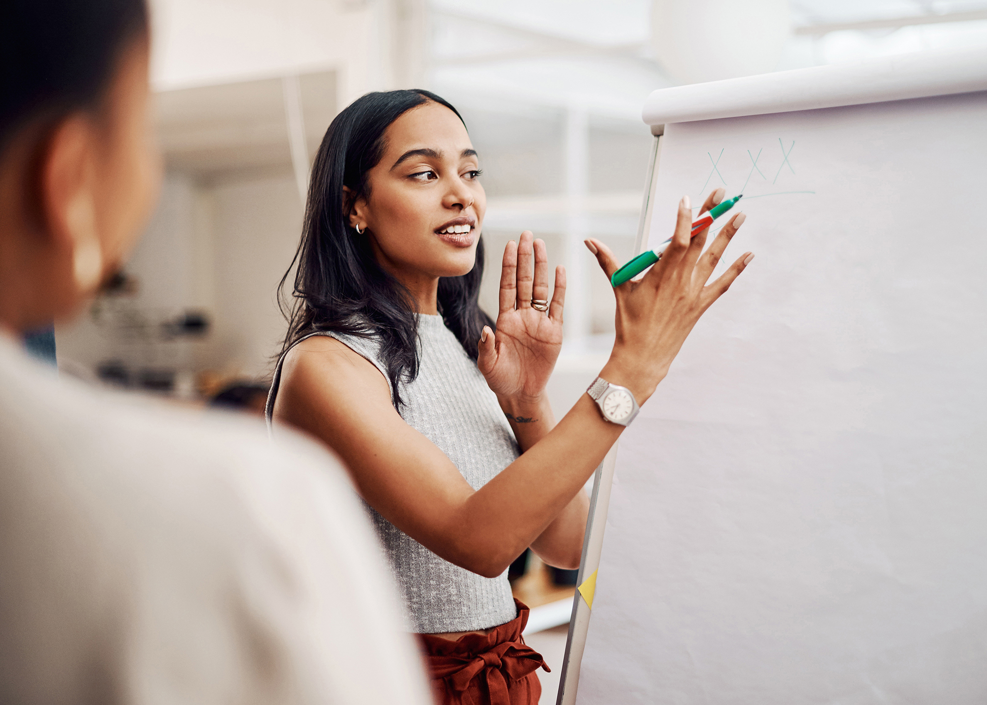 woman mentoring colleague while gesturing to a blank paper roll